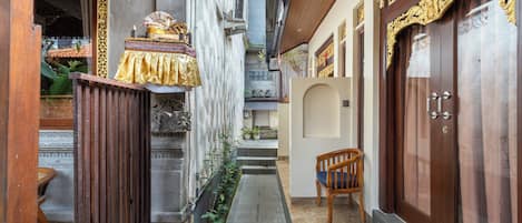A narrow alleyway with a wooden bench, a door with ornate carvings, and a small staircase leading to a higher level.
