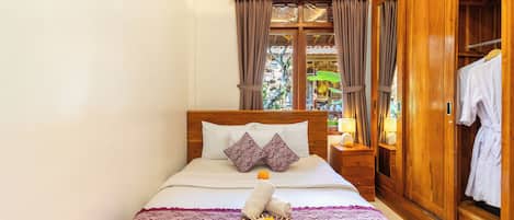 Ein Hotelzimmer mit einem hölzernen Bett, einem Kleiderschrank und einem fensterbelaubten Fenster.