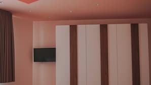 A bedroom with a bed, a flat-screen TV, and a wardrobe.