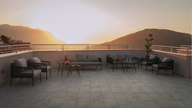 A terrace with seating and tables, overlooking a mountainous landscape.