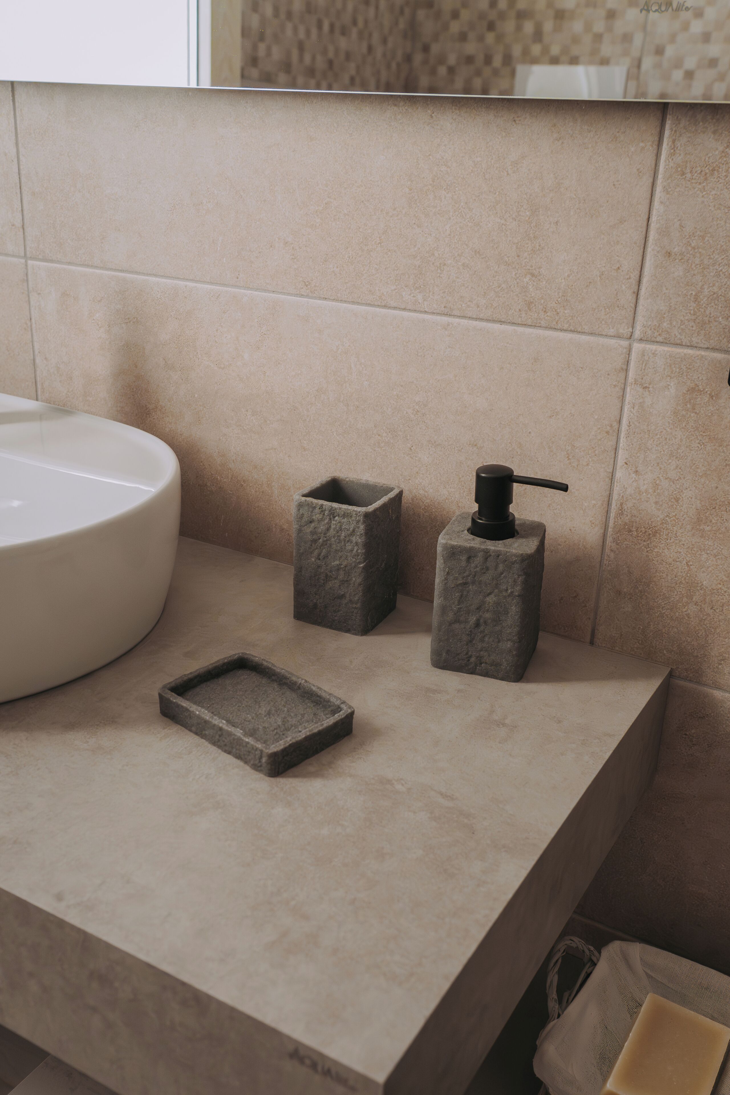 Un baño con un lavamanos grande blanco, un dispensador de jabón y un pequeño jabonero rectangular sobre una encimera color beige.