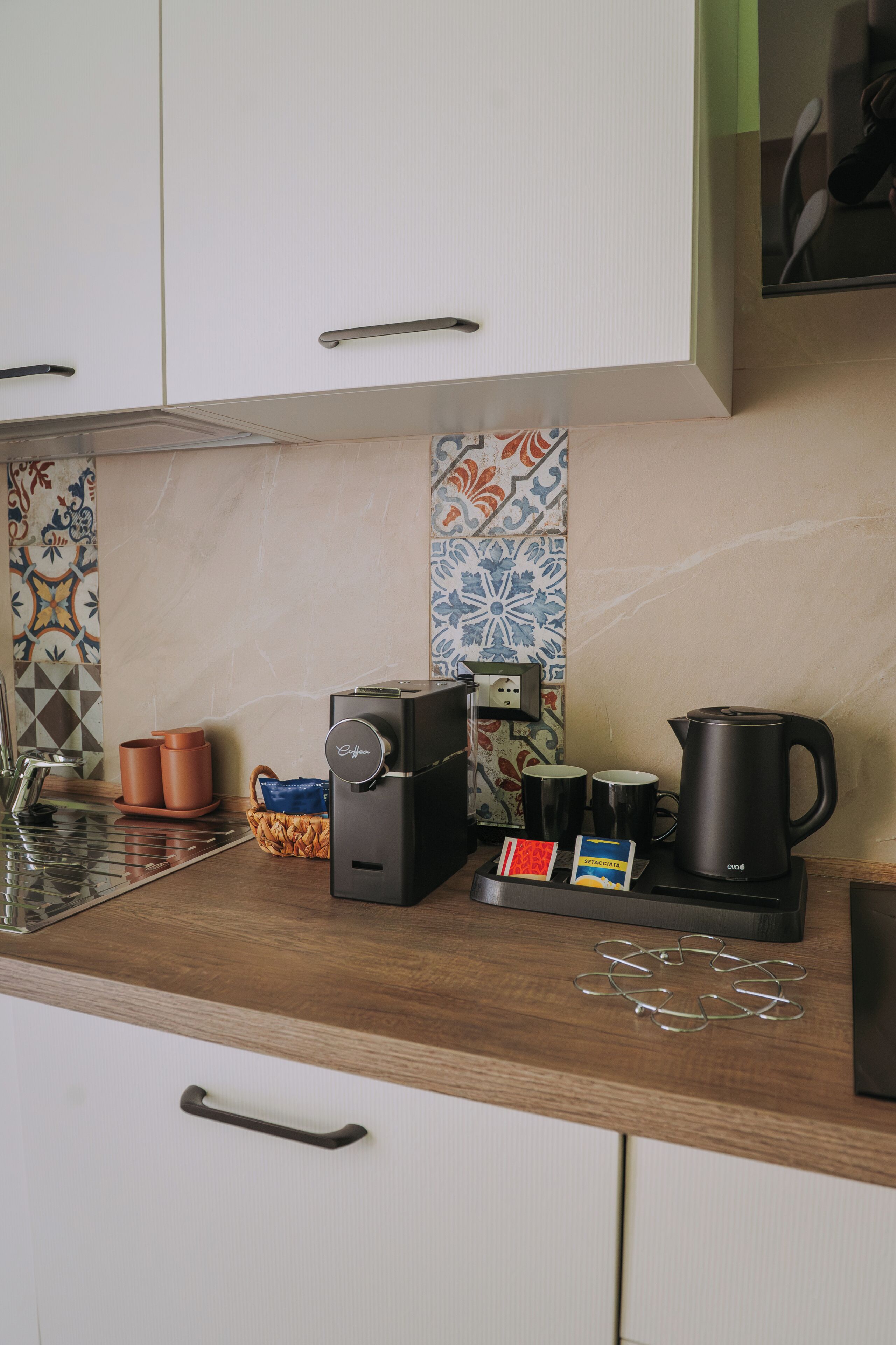 Una cucina con una macchina del caffè, un bollitore e un cesto sul piano di lavoro.