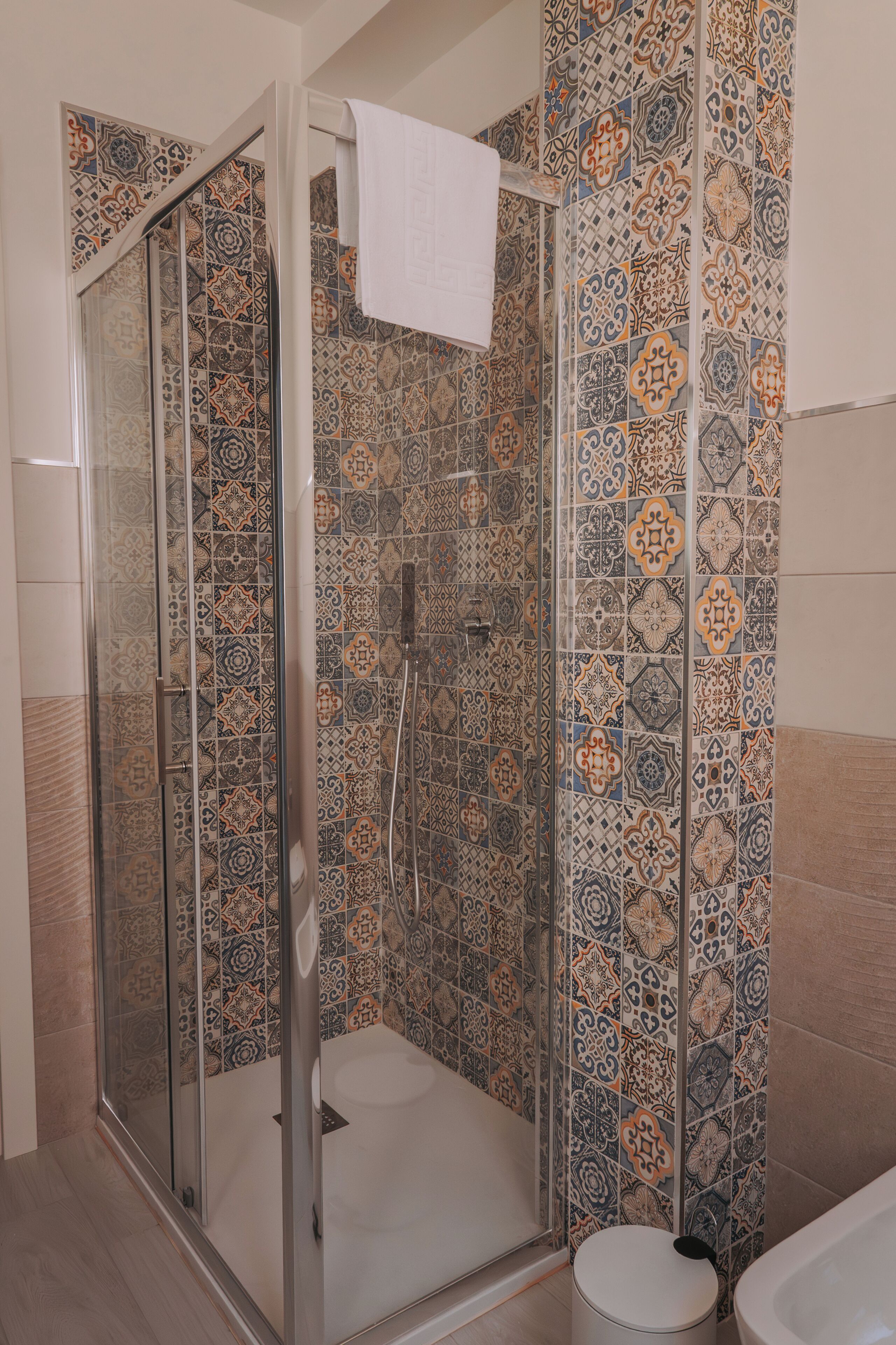 A shower with a glass door and a white towel hanging on the door handle.