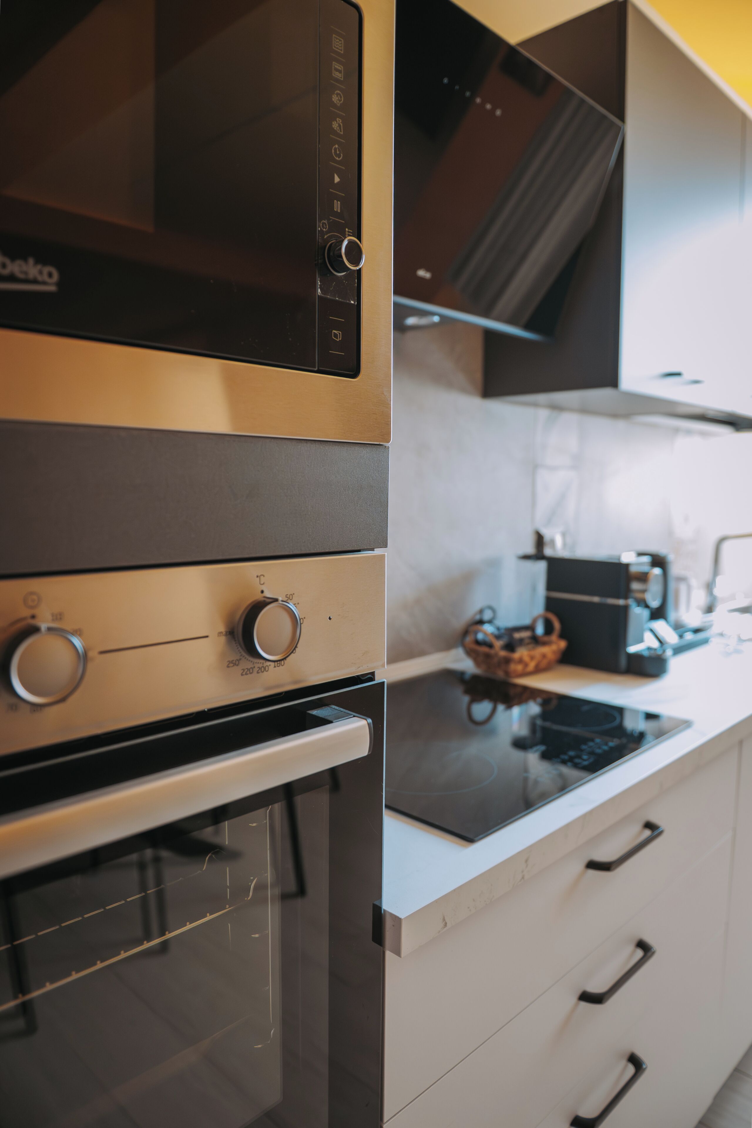 A kitchen with a built-in oven and microwave, a stove, and a countertop with a coffee maker.