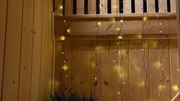 A wooden interior with a balcony, string lights, and a small plant.