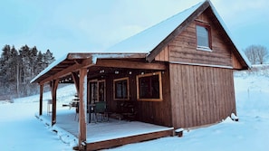 A wooden cabin with a covered porch and a single window.
