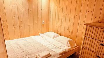 A wooden room with a bed, a cabinet, and a ceiling with exposed beams.