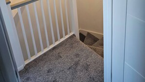 Eine Treppe mit weißer Geländer, Teppichstufen und einer Lampe.