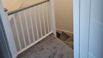 A staircase with a white railing, carpeted steps, and a light fixture.