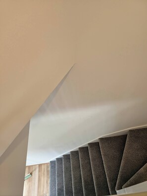 A staircase with a wooden finish and a white ceiling. - The Chilux Stylish Apartment (Rainham)