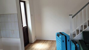 Ein Zimmer mit Holzboden, einer Treppe und blauem Gepäck.