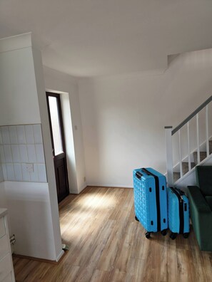 A room with a wooden floor, a staircase, and blue luggage. - The Chilux Stylish Apartment (Rainham)