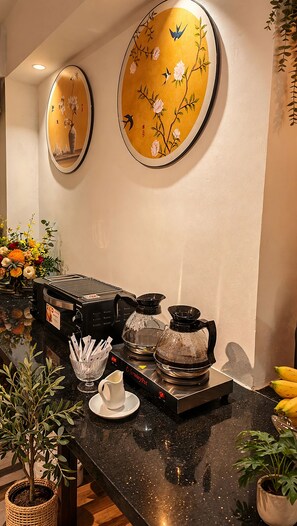 A buffet setup with a coffee machine, a pitcher, and a bowl of snacks. - De Rond au Lac (Hanoi)
