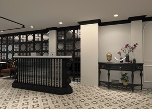 A reception area with a black and white patterned floor, a black console table with a decorative back panel, and a black console desk with drawers and a vase with flowers. - De Rond au Lac (Hanoi)