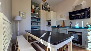 A kitchen with a black countertop, white cabinets, a built-in oven, and a microwave. - Château de Roche – French Château Living near Toulouse (Pechbonnieu)