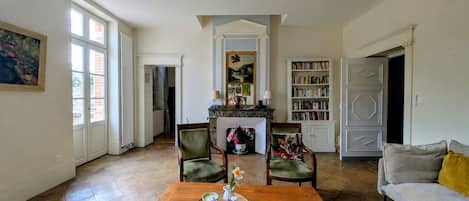 Un salón amplio con chimenea, ventilador de techo y estantería.