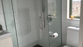 Un baño moderno con ducha de vidrio, inodoro y ventana.