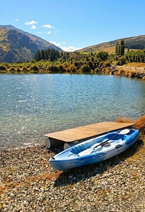 A kayak on a wooden dock by a clear lake with mountains in the background.