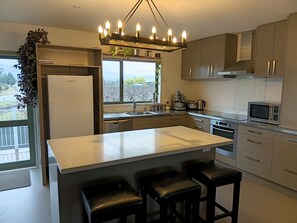 Una cocina moderna con una isla central, electrodomésticos de acero inoxidable y vistas a través de la ventana.