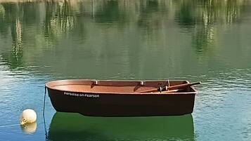 A small boat named 'Paradise on Pearson' anchored on calm water.