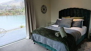 A bedroom with a bed, a clock, and a view of a lake.