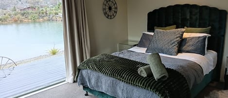 A bedroom with a bed, a clock, and a view of a lake.