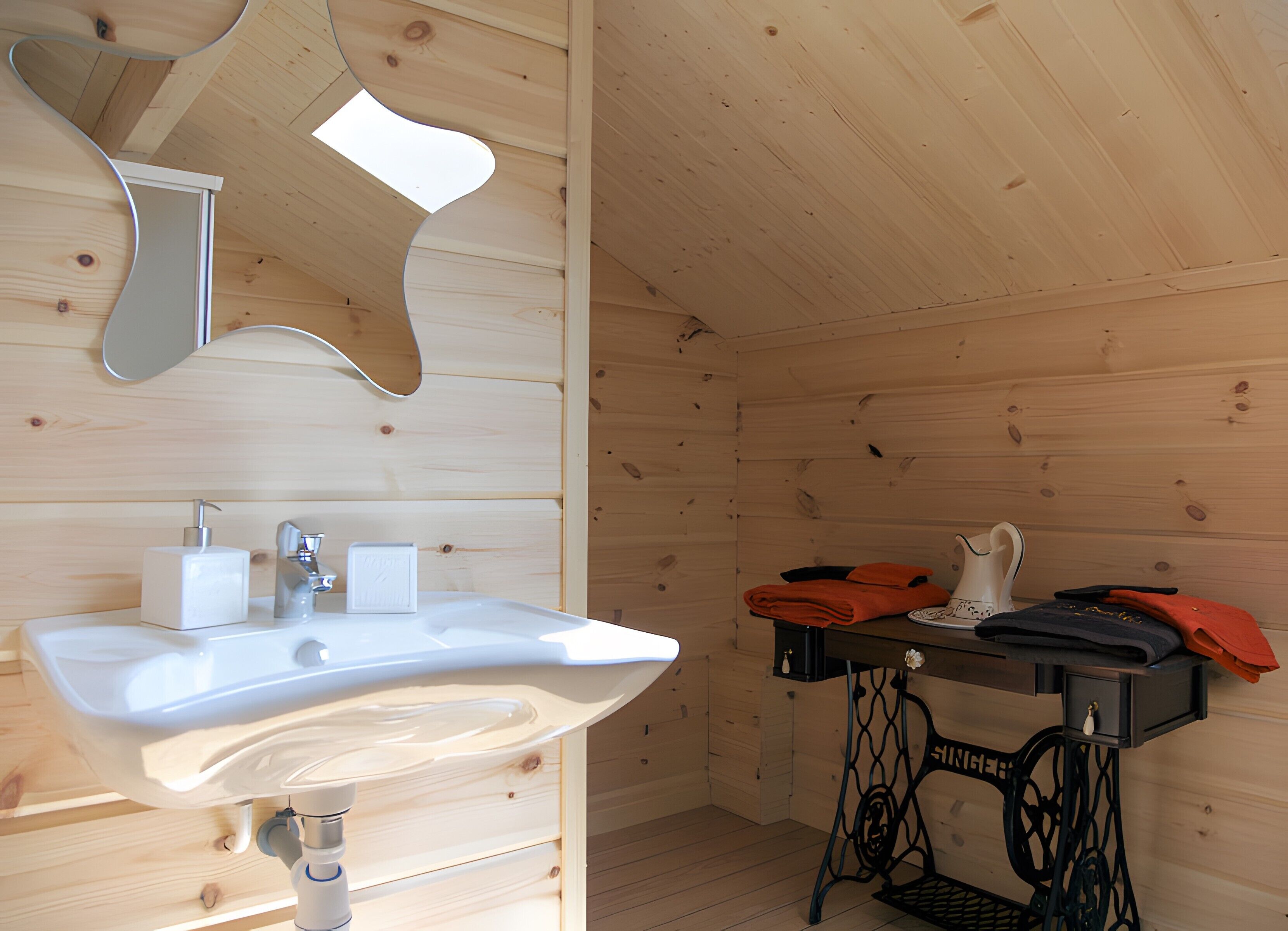 A wooden cabin interior with a sink, mirror, and a sewing machine on a table.