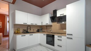Una cocina moderna con armarios blancos, horno negro y encimera de madera.