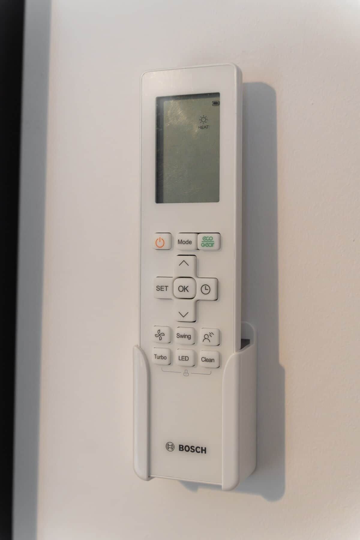 A white Bosch wall-mounted thermostat with a digital display, control buttons, and a small storage compartment.