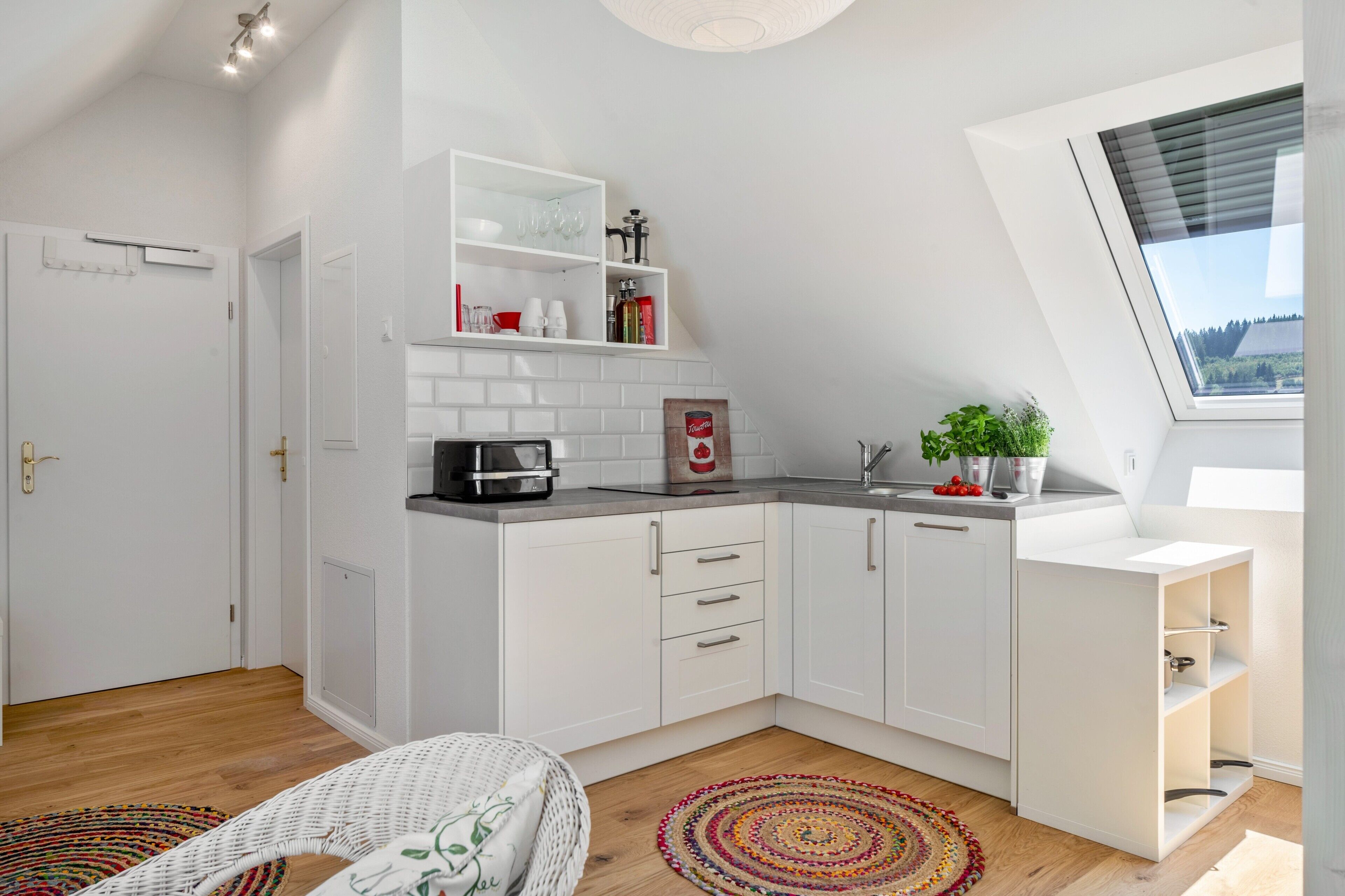 A modern kitchen with white cabinetry, a built-in oven, and a window with a view.