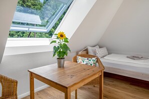 Una stanza luminosa con un tavolo di legno, un girasole in vaso e una sedia in vimini.