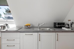 A modern kitchen with a stainless steel sink, a kettle, a coffee maker, and a fruit bowl on the counter. - Apartment 'Fuchs und Has Feldberg - Neu Eröffnung Juli 2026 - App 7/ Gemeinschaftsgarten/ Sauna/ Aussicht' (Feldberg)