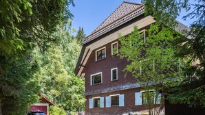 Un edificio a due piani con facciata in mattoni, diverse finestre e tetto spiovente.