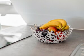 Uma tigela decorativa branca com frutas sobre uma mesa.