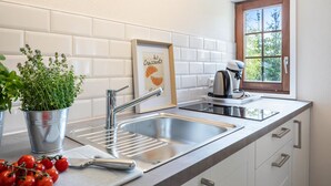 Et moderne køkken med en stålvask, elkedel og en urteplante i potte.