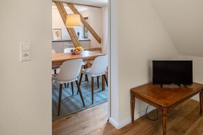 Un soggiorno moderno con un mobile TV in legno, una TV a schermo piatto e un'area pranzo con tavolo in legno e sedie bianche.