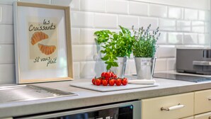 Een keukentrap met een lijst, een bloempot en een bos tomaten.