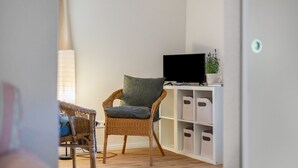 Ein Zimmer mit einem Korbsessel, einem Flachbildfernseher auf einem weißen Schrank und Stauraumeinheiten.