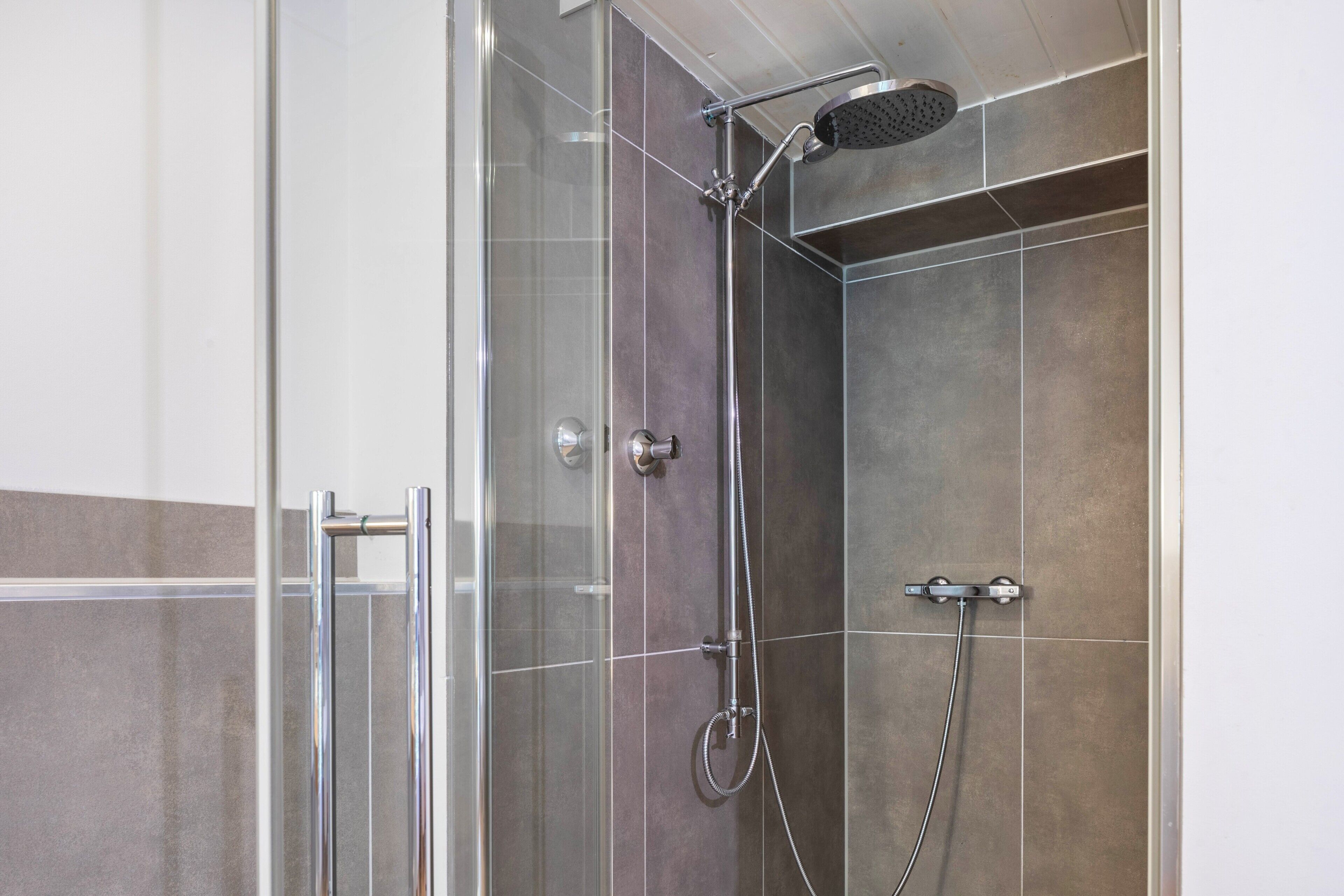 Een moderne douche met een handdouche en een regendouchekop.