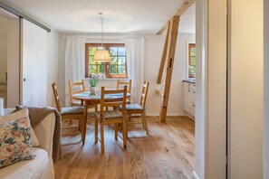 Un coin repas avec une table et des chaises en bois, une lampe suspendue et une fenêtre avec des rideaux.