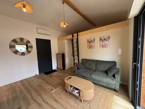 Ein Wohnzimmer mit einer Couch, einem Couchtisch, einer Leiter, einer Tür und Wandbildern.