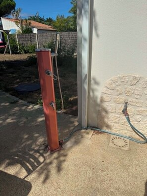 A red fire hydrant connected to a hose near a building's exterior wall. - Small Seaside House, Rated 3* (Saint-Denis-d'Oléron)