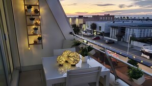 A balcony with a table and chairs, potted plants, and a view of the cityscape during sunset. - Apartment 'Carpe Diem' with Bassin View, Balcony and Wi-Fi (Arcachon)