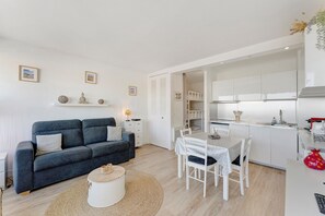 Ein moderner, kompakter Wohnraum mit Sofa, Esstisch und Küchenzeile.