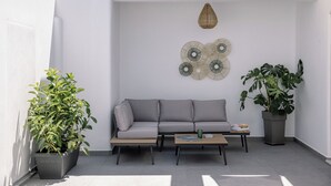A modern living space with a grey sofa, a wooden coffee table, and two potted plants. - Trinity Secret Villas (fira)