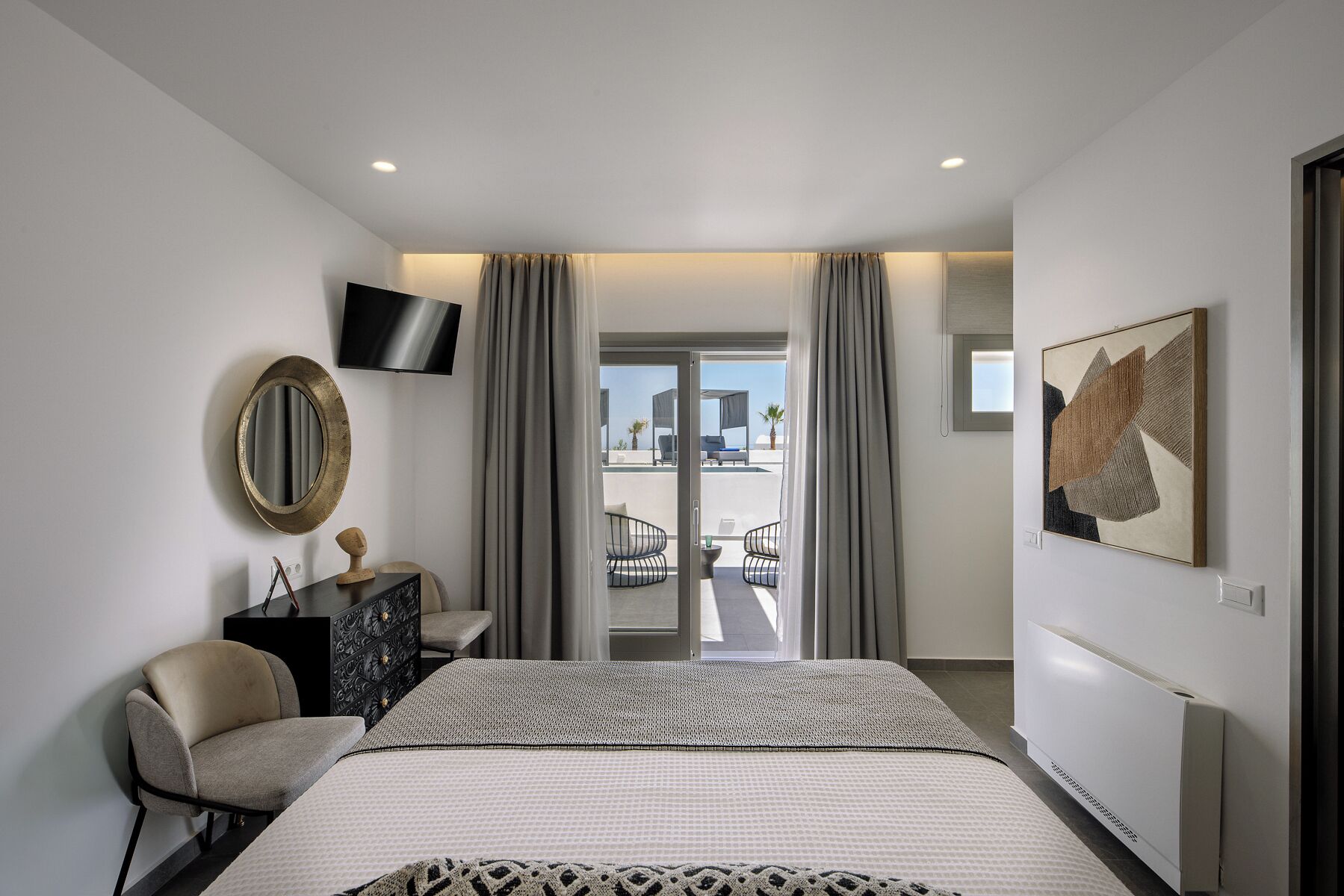 Un dormitorio con cama, televisor, espejo, cómoda y vistas al exterior.