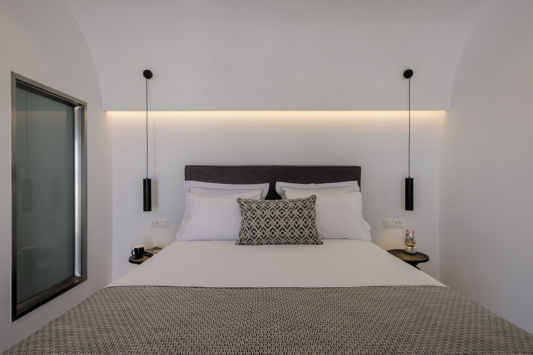 Ein modernes Hotelzimmer mit einem großen Bett, zwei Nachttischen, einem Wand-Fernseher und einem gemusterten Teppich.