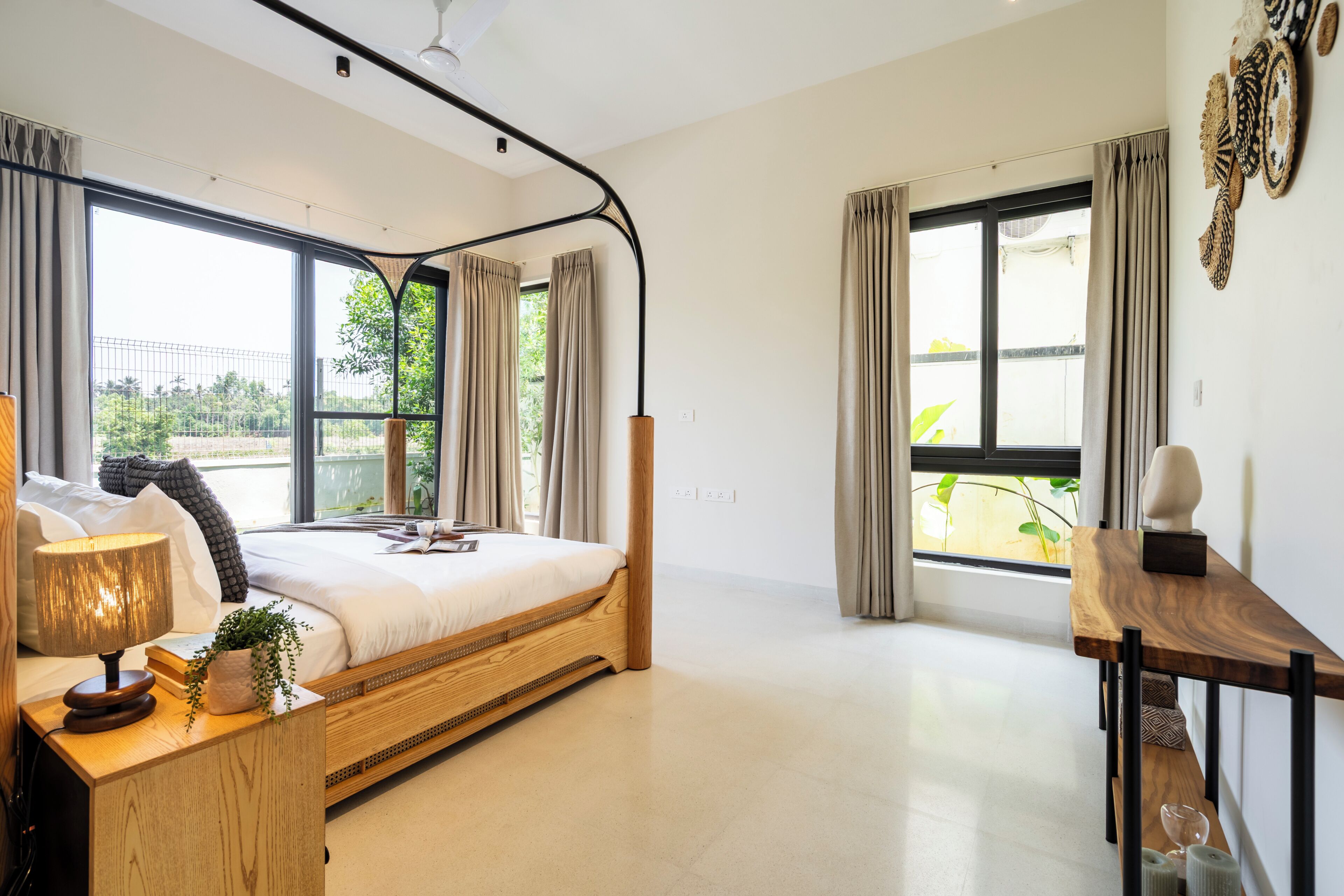 Un dormitorio moderno con cama, mesita de noche, l ámpara y vistas a espacios verdes.