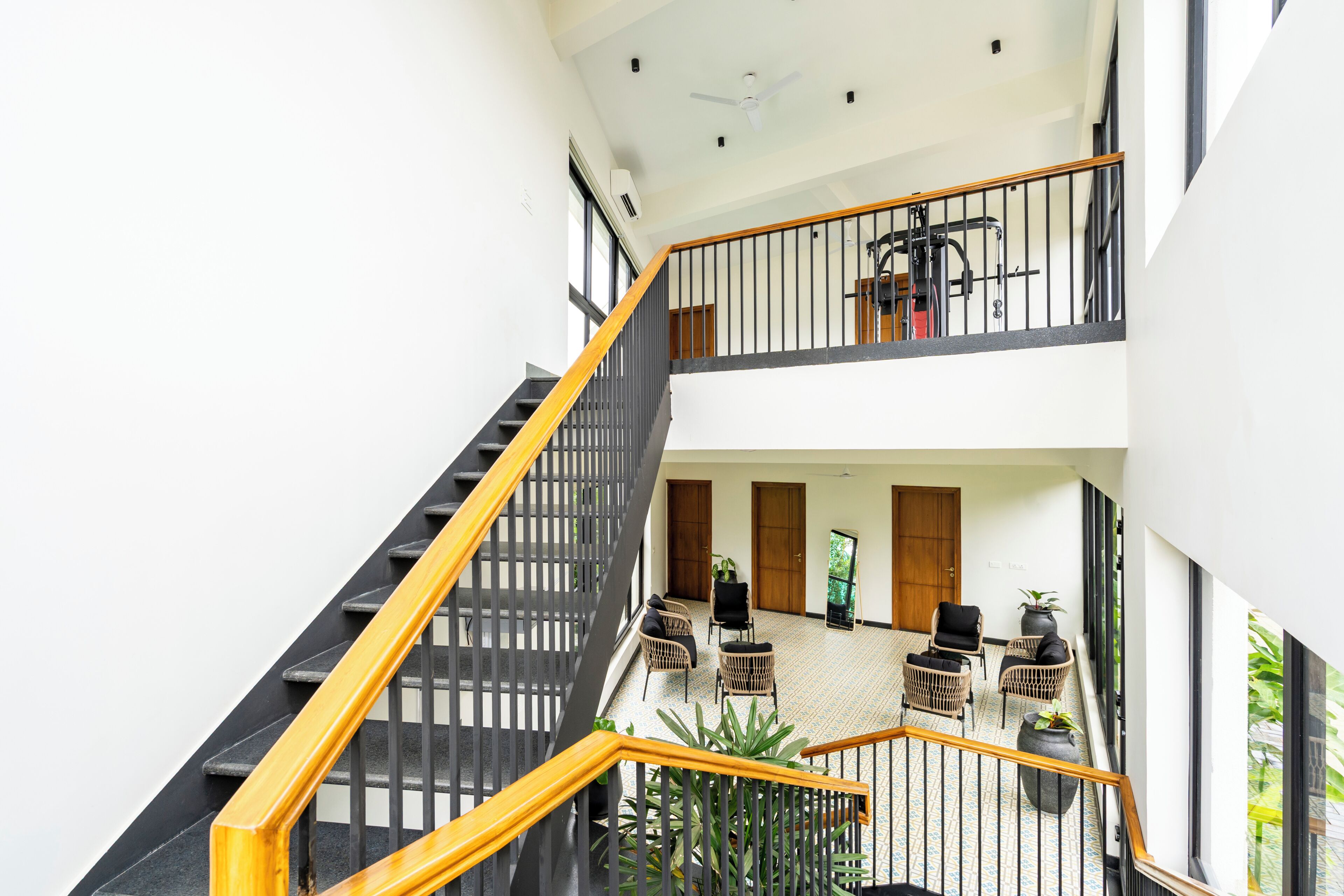 Un interior de varios niveles con escalera, área de estar y ventanas amplias.