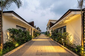 A corridor flanked by modern buildings with a paved walkway, surrounded by greenery.